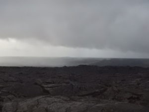 Do you see the steam rising from the lava flow as it travels down the mountain in the distance?